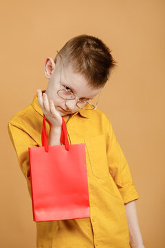 Shopping on black friday. Little boy holding shopping bags on yellow background. Shopper with many colored paper bags. Holidays sales and discounts. Cyber monday. High quality photo