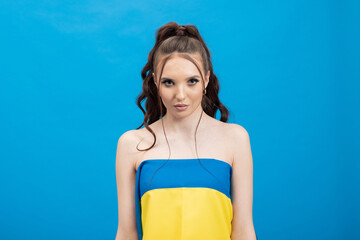 A sad serious woman wearing a Ukrainian blue and yellow flag on a colorful background.