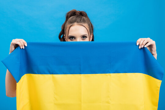 Portrait Of A Woman With Only Her Eyes Visible, Her Face Hidden Behind A Blue And Yellow Flag Of Ukraine, Colorful Background, Expressions Of Solidarity.