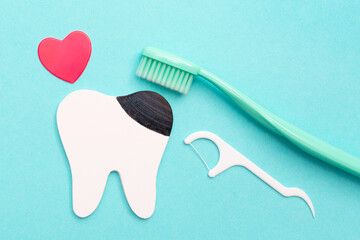 Model of a tooth with caries. Toothbrush and hearts on blue background. Flat lay. Top view. Dental care kit. Oral hygiene.