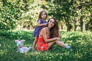 young mother in a red dress with her daughter in the park