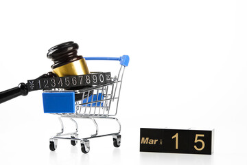 Closeup of a shopping cart with a hammer and a price tag, sign march 15th- world consumer rights day