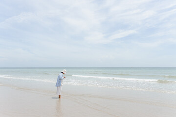 Beautiful beautiful young woman using mobile phone at beach. woman standing take photograph sandy beach