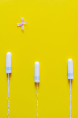 top view of bow near hygienic tampons on bright yellow background.