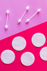 top view of white cotton pads and ear sticks on bicolor pink and violet background.