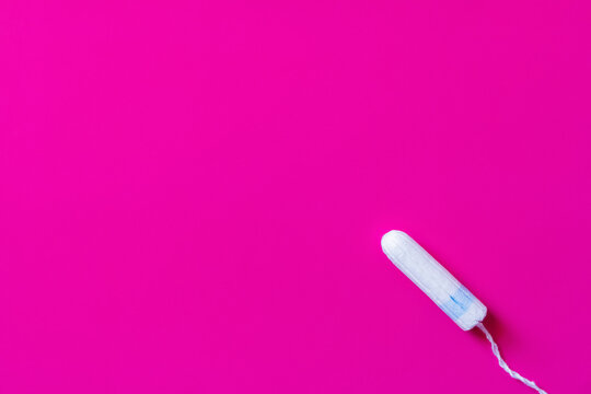 top view of hygienic tampon on purple background with copy space.