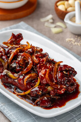 ayam goreng mentega or fried chicken with soy sauce, butter and onion served on white plate.