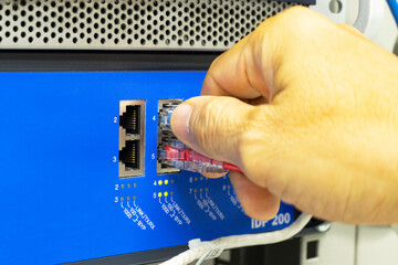 Hand of a man holding The network cables to connect the port of a switch to connect internet network, concept Communication technology