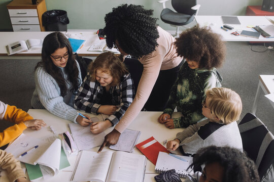 Teacher pointing at book while teaching in classroom