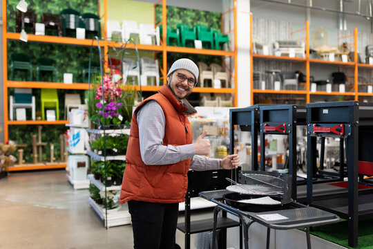 a customer in a picnic supply store picks up a grill and barbecue for outdoor recreation