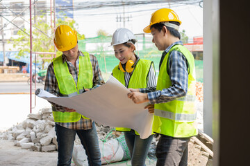 Asian engineer or Young Female Architect put on a helmet for safety and talk with a contractor on a construction building factory project, Concept of Teamwork, Leadership concept.