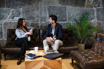 Delegates sitting on sofa while planning at seminar in convention center