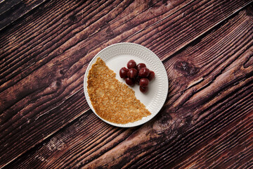 Taken from above flat lay picture of half a pancake with canned black cherries.