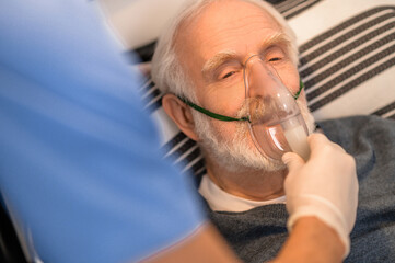 Experienced nurse conducting an oxygenation procedure on a bedridden man