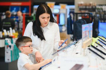 Fototapeta premium woman with son in store buying new phone.