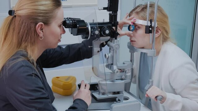 Optometrist examining the eyesight of woman with a slit lamp