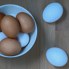 several fresh chicken eggs in a ceramic cup on a wooden background. Healthy eating concept