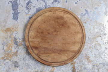 Round kitchen cutting board in brown color on a shabby iron plane