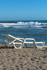 Fototapeta na wymiar wide sandy beach with a plastic deck chair at the edge of the blue sea