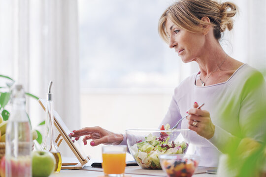 Woman having lunch and connecting with her tablet