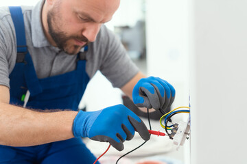 Professional electrician testing an outlet - obrazy, fototapety, plakaty
