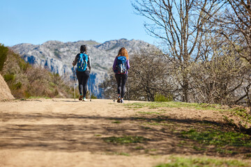 Obraz premium Two female backpacker hikers on a pathway. Mountain trekking