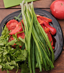 Various raw chopped fresh vegetables with water drops on a wooden table.