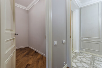 An interior space with light-colored walls with a view of the parquet floor on one side .   and the ceramic coating on the other.