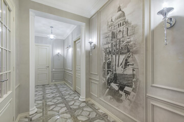 A corridor with light walls, brown tiles on the floor, stylish lamps. The wall is decorated with an original painting.
