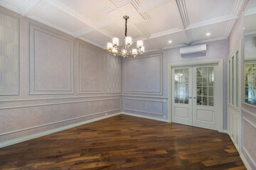 A spacious living room without furniture with original decorated walls and ceiling. Brown parquet....
