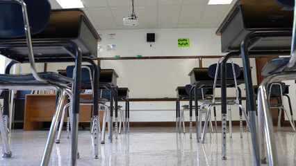 Showing empty school classroom with chairs under desks. Concept for pandemic.