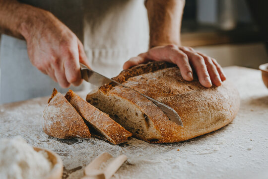 Young man in apron cutting homemade bread