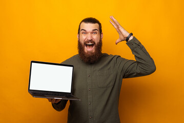 Ecstatic bearded man holding a laptop with blank screen is mind blown.