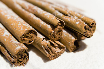 Stack of dry cinnamon with icing sugar as snow on a white background