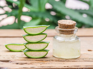 Fresh aloe leaves and aloe gel in the cosmetic jar on wooden table.