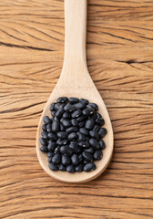 Black beans in a spoon over wooden table