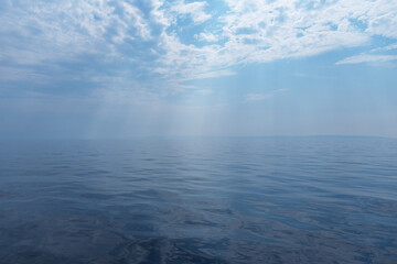 Calm sea and cloudy sky pierced with sun rays. Beautiful nature background.