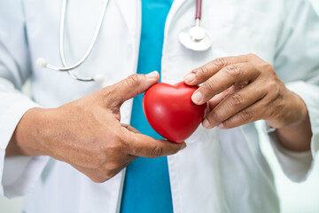 Doctor holding a red heart in hospital ward, healthy strong medical concept.