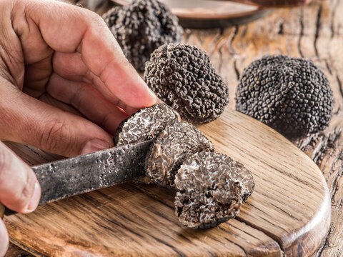 Slicing of black winter truffles. Black truffles and truffle slices on wooden board.