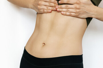 Cropped shot of a young slim woman with toned stomach demonstrating her abs isolated on a white...