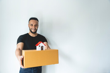 A white man holding a box with a model house above. moving house idea find a new place to live