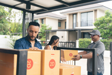 A couple is picking up goods from a delivery man at home. checking product