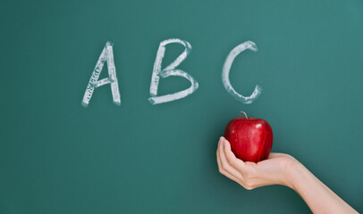 Apple in hand and abc written on blackboard