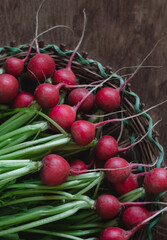 Wicked basket with fresh red radish on a wooden background.
