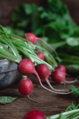 Red radish with green leaves on a dark kitchen table.