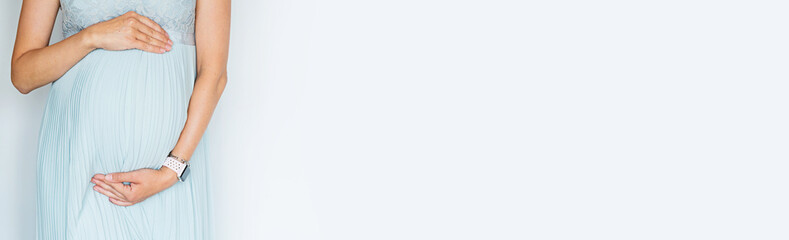 Closeup photography of young Woman touching hands her big belly in pastel blue dress Isolated on white background with copy space. Skin care with moisturising cream against stretch marks. Emotional