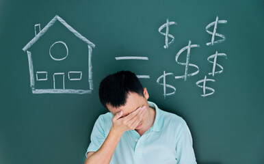 Man in front of drawing house and money on blackboard