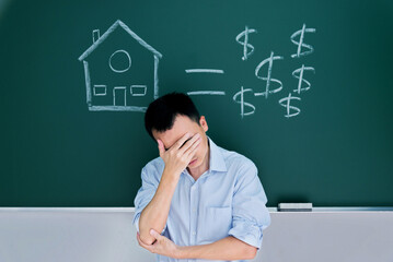Man in front of drawing house and money on blackboard