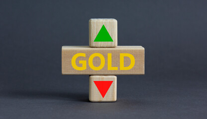 Gold price symbol. A wooden cube with arrow symbolizing that Gold price are going down or up. Beautiful grey table grey background. Business and gold price concept. Copy space.