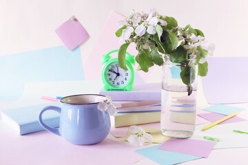 Back to school, alarm clock, apple tree flowers bouquet, stack of books, cup of tea, and stationery on the table, education, vacation time